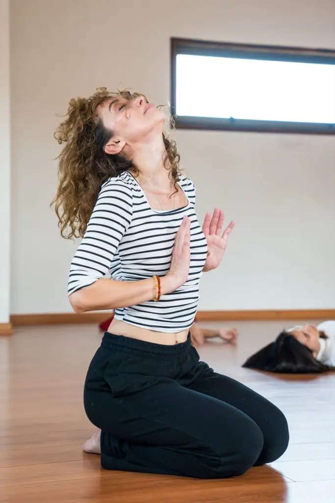 Alumna de rodillas con la cabeza hacia atrás, en una vivencia de danza