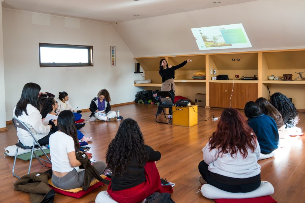 Clase teórica: docente presentando frente al grupo sentado en cojines