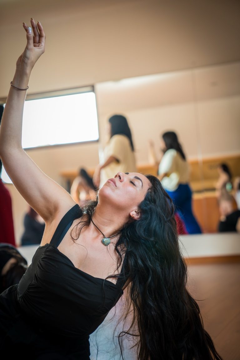 Alumna danzando con un brazo hacia el cielo y los ojos cerrados